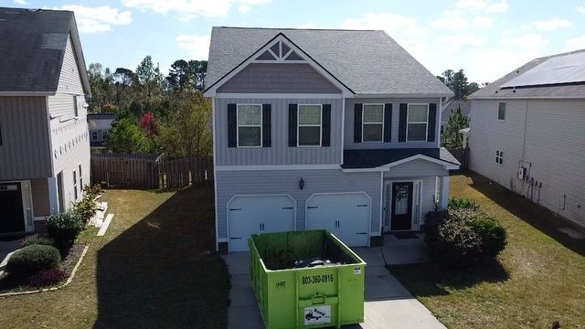 An aerial view of a house with a green dumpster in front of it.