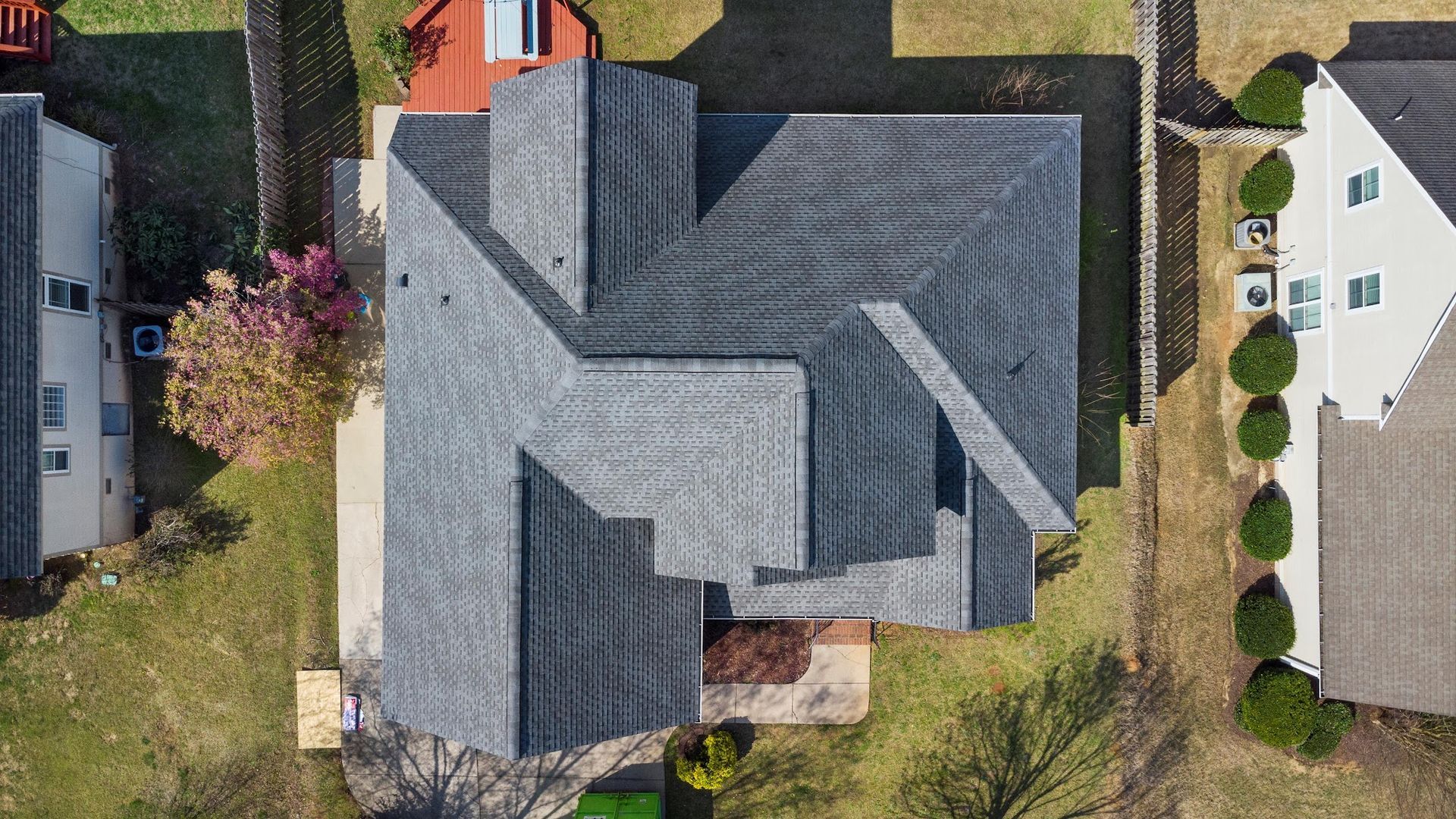 An aerial view of a house with a gray roof in a residential area.