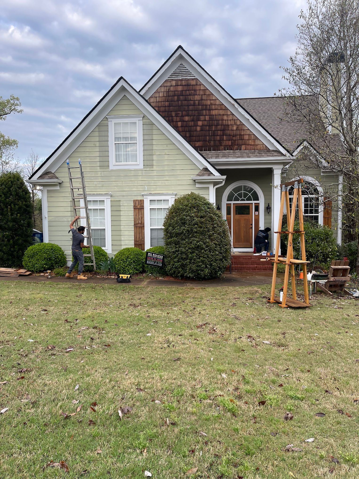 A house with a ladder in front of it is being painted.