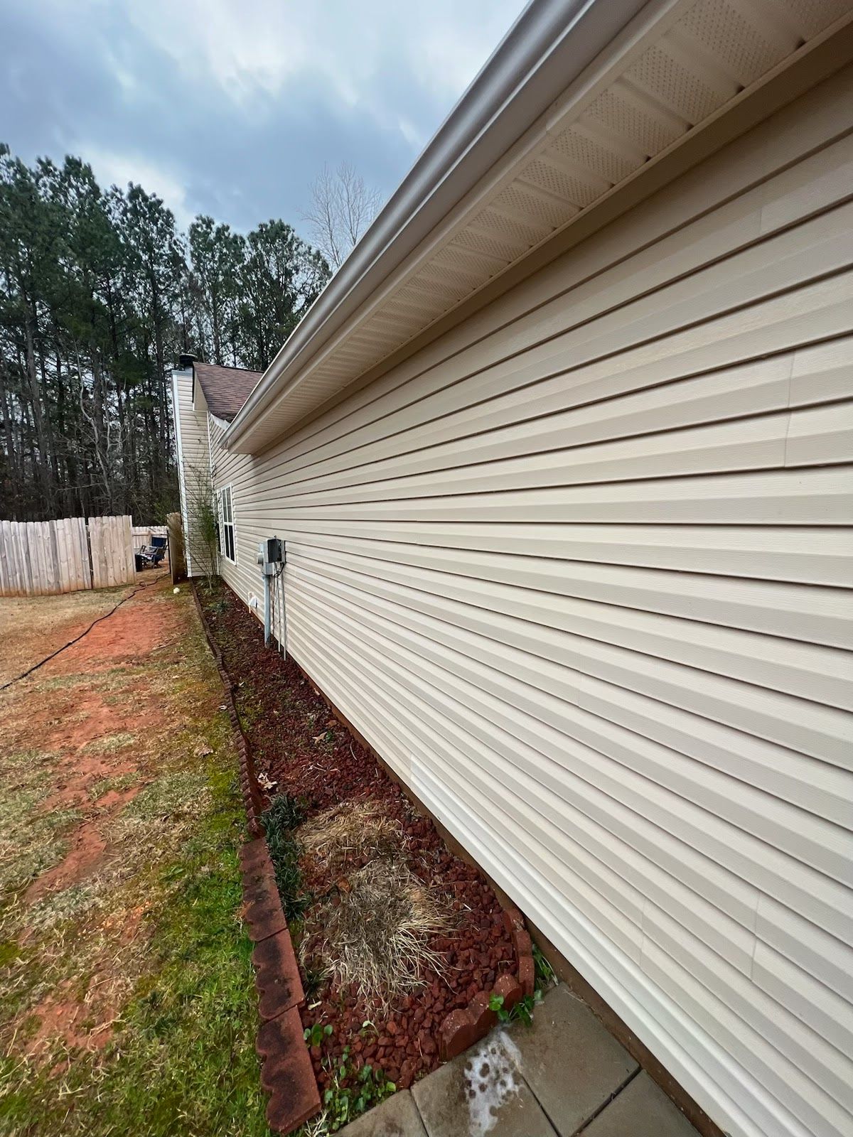 The side of a house with white siding and a gutter.