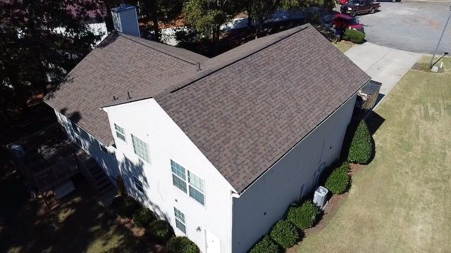 An aerial view of a white house with a brown roof.