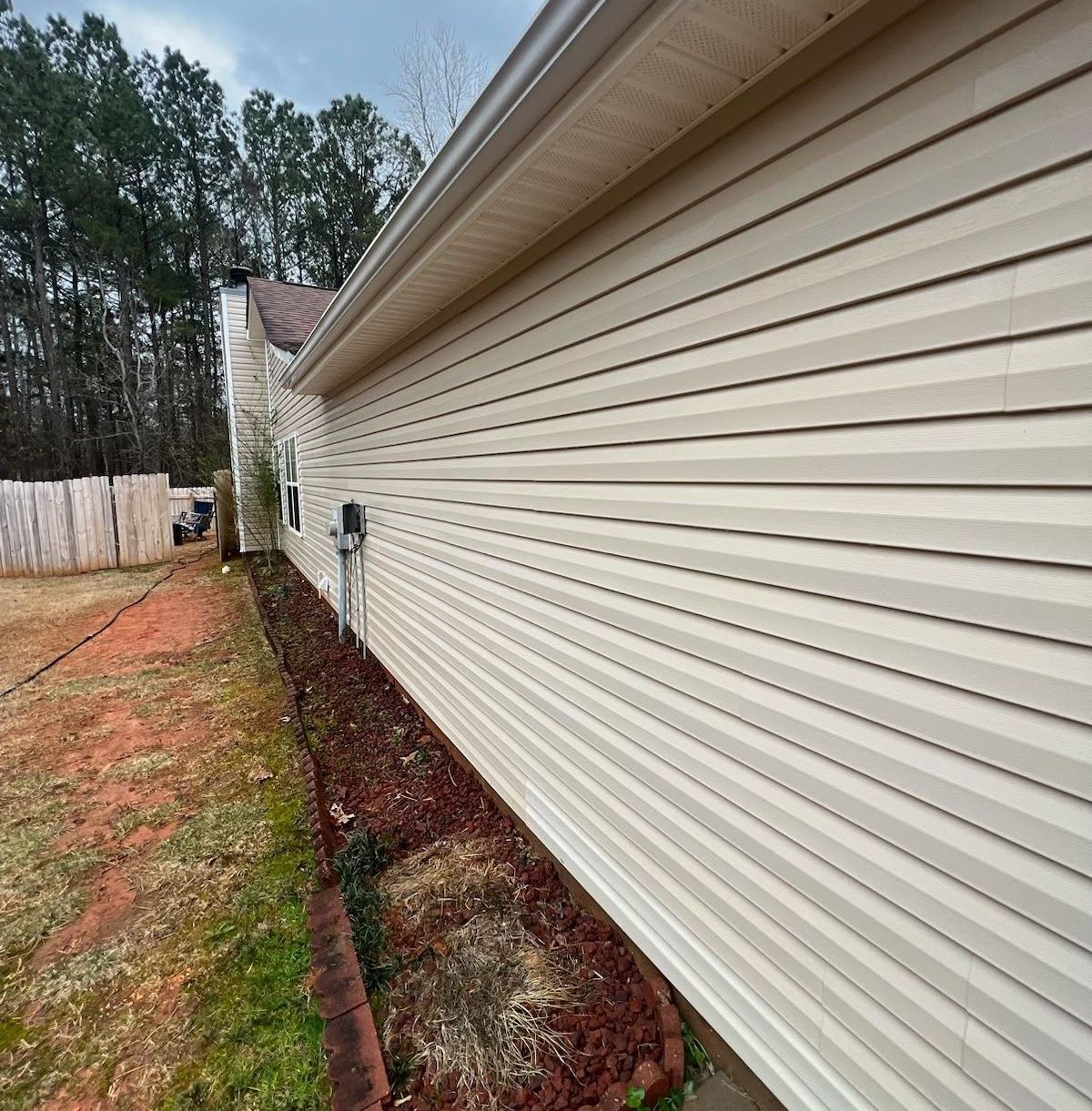 The side of a house with white siding and a gutter.