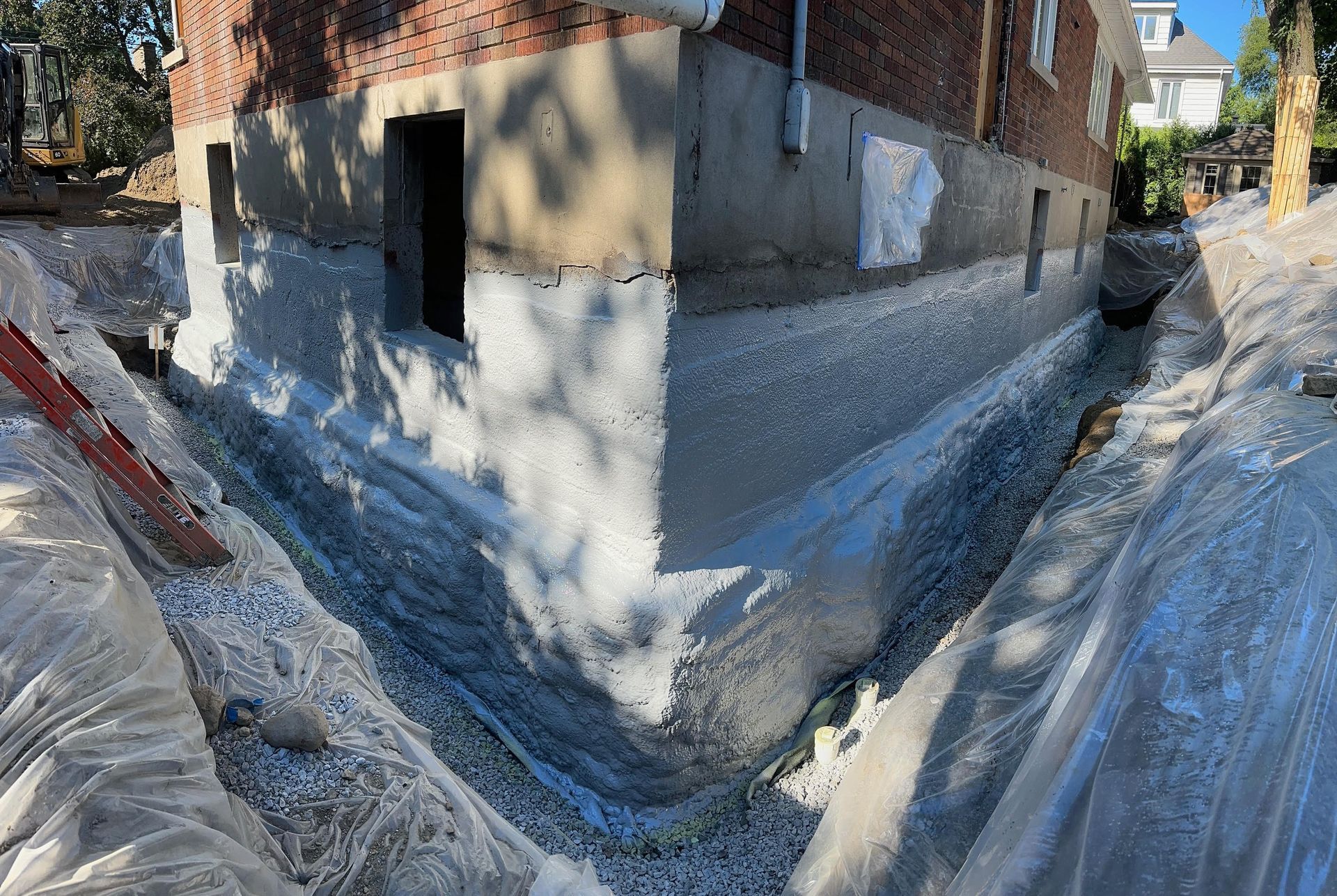 Chantier de construction avec travaux de fondation, bâtiment en briques, tranchée.