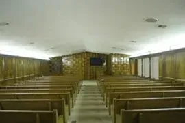 Empty church sanctuary with wooden pews, central aisle, and a raised altar at the front