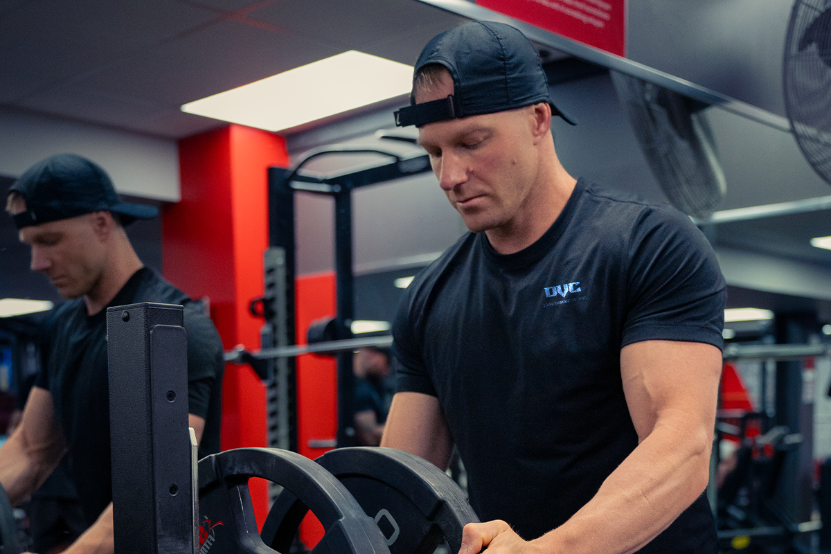 A man is lifting a barbell in a gym.