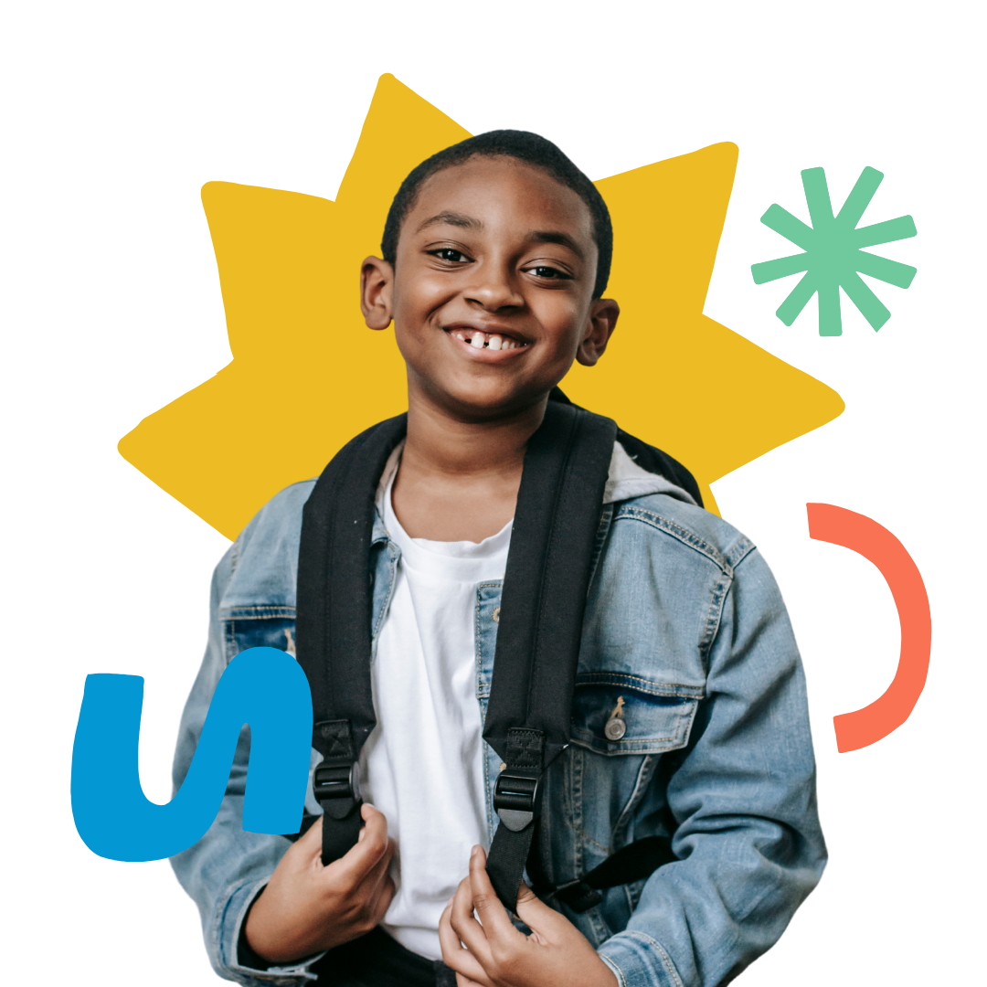 A young boy wearing a backpack and a denim jacket is smiling.