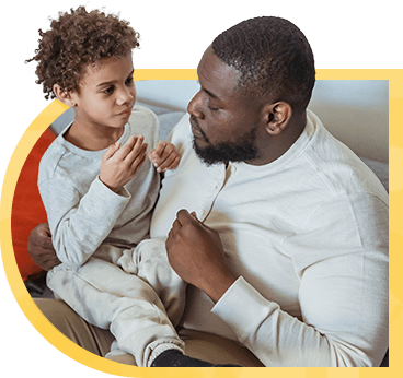 A father speaks with his son, who sits in his lap.