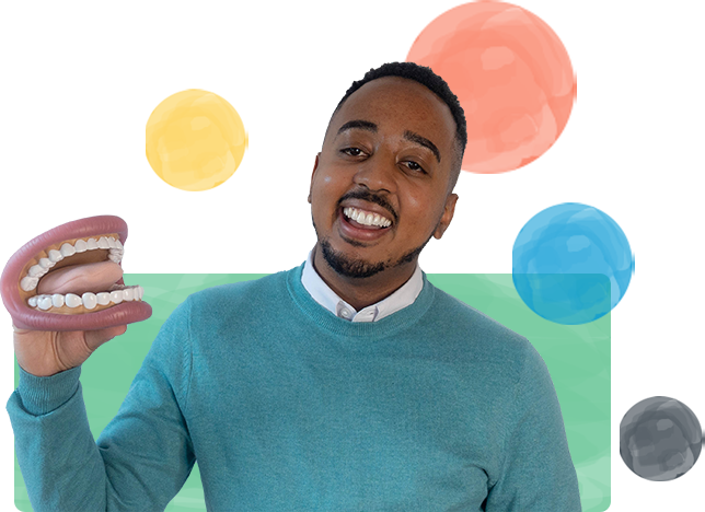 Child speech-language pathologist Myles Nobles smiles while holding up a 3-dimensional plastic model of an open mouth with a large tongue.