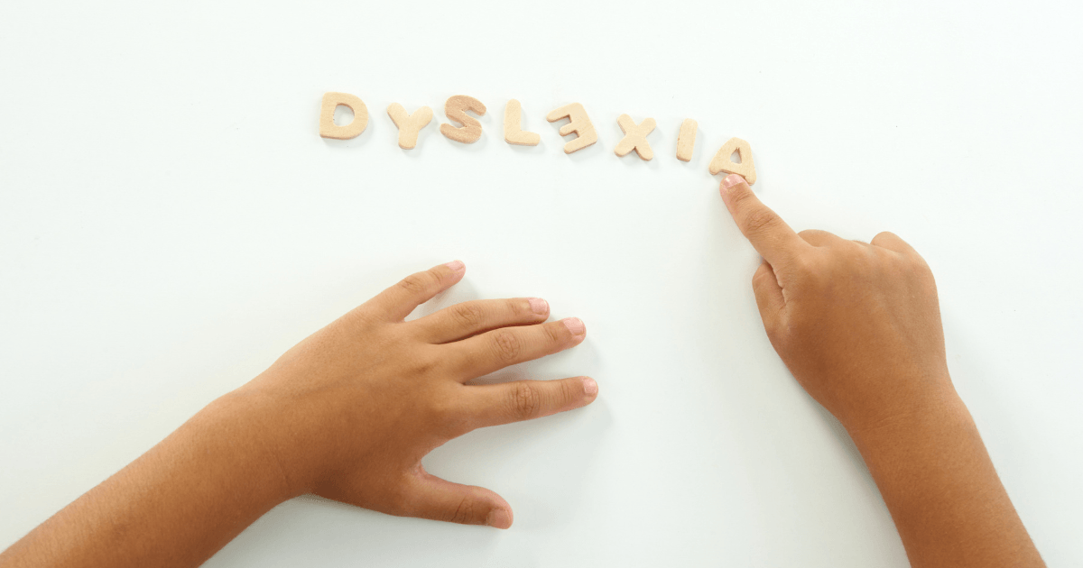 hands pointing the word dyslexia made from wood