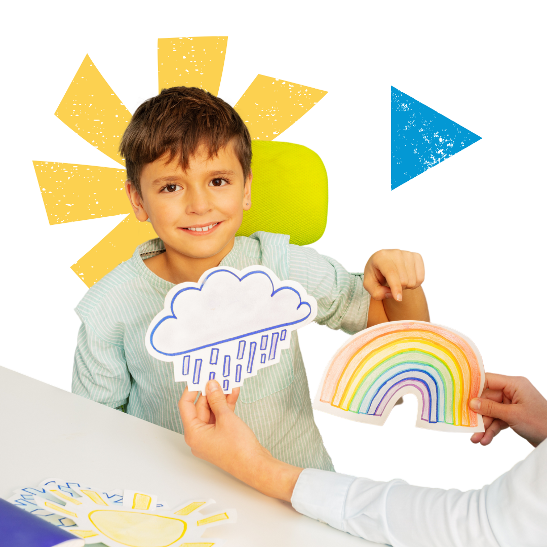 A little boy is sitting at a table pointing a rainbow and a cloud photo