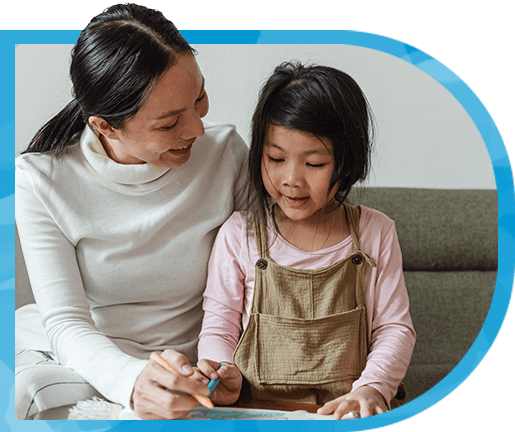 A mother helps her young daughter write.