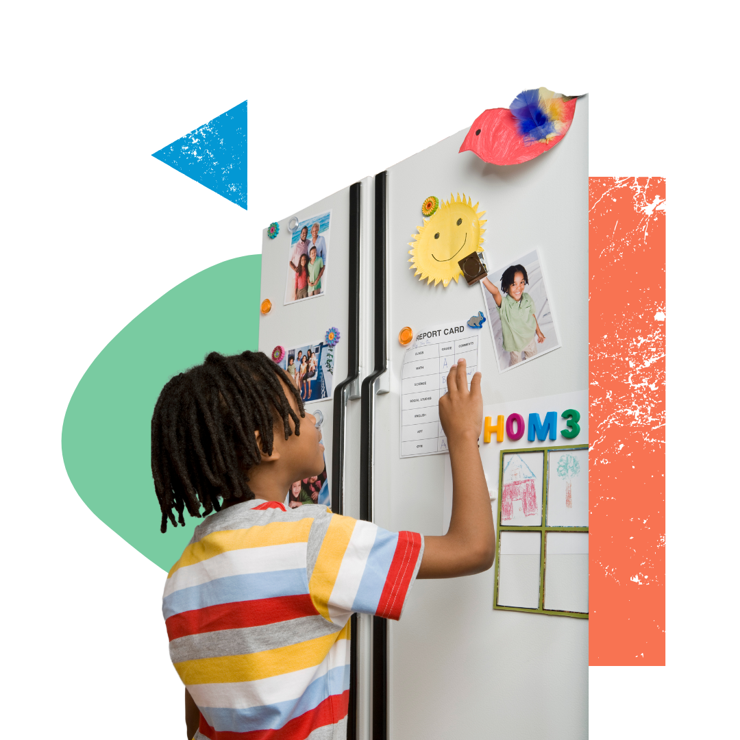 A young boy is standing in front of a refrigerator with visual calendar on it