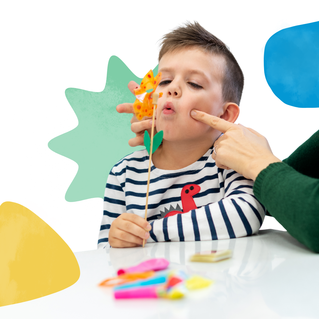 A little boy is sitting at a table playing with a toy windmill.