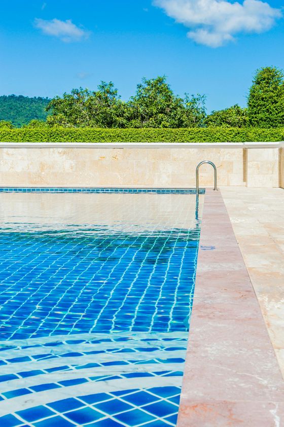 A swimming pool with blue tiles and a ladder leading to it.