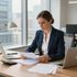 Business professional reviewing papers at a desk in a bright office with laptop, calculator, and lamp