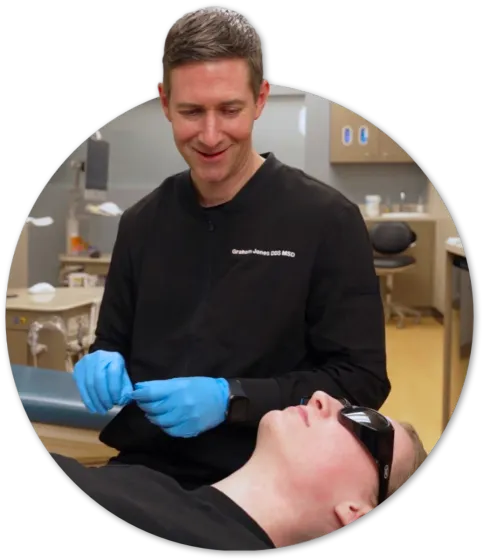 An orthodontist smiling at a patient in a clinic chair