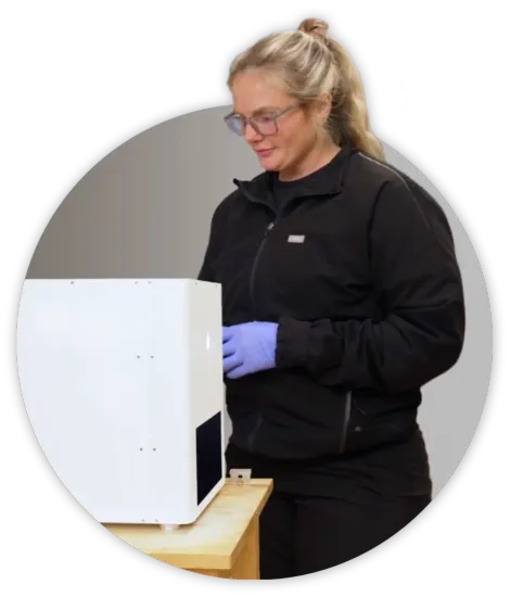 A woman in a black jacket and blue gloves is working on a machine