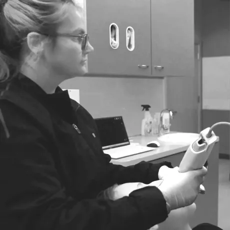 A woman holding an intraoral scanner in a patients mouth