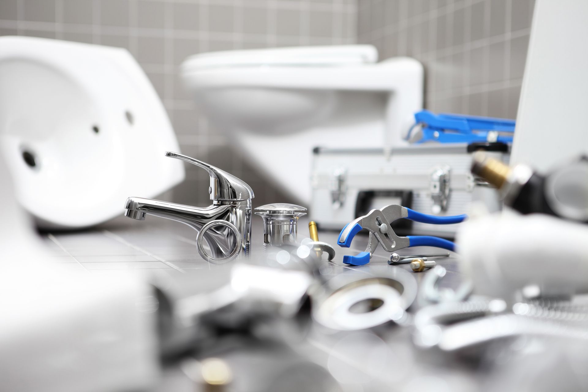 Plumber equipment and parts are laying on the floor of a bathroom.