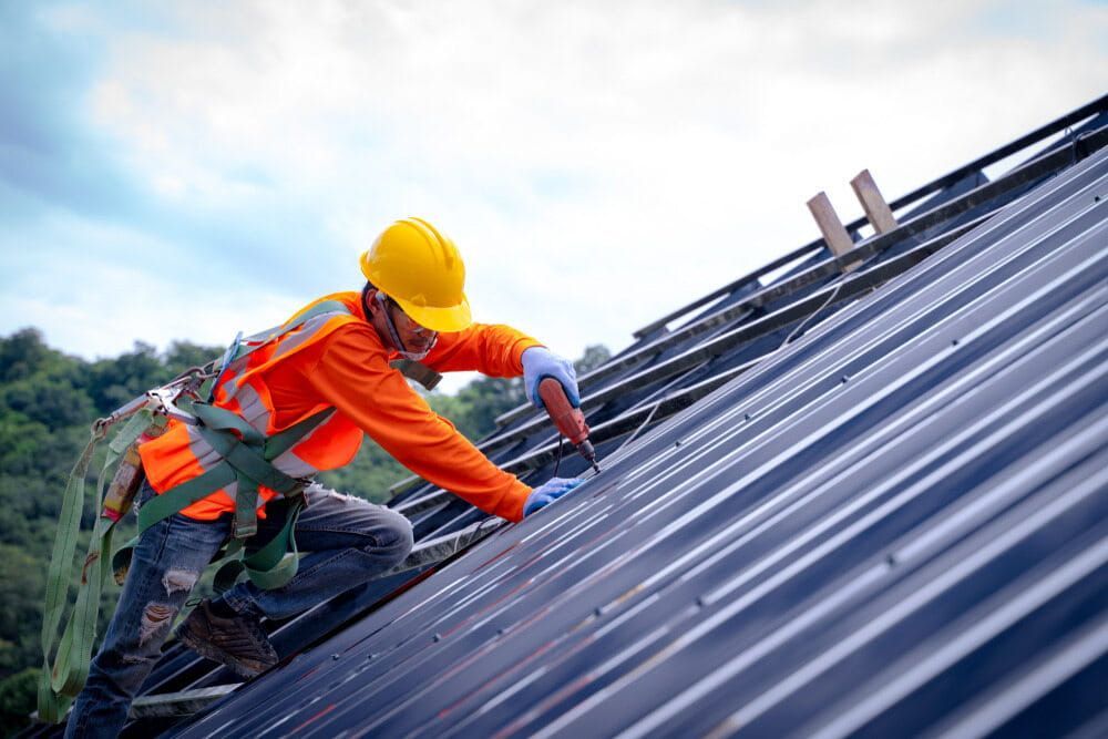 A Construction Worker Is Working on The Roof of A Building — Roof Masters NQ in Douglas, QLD