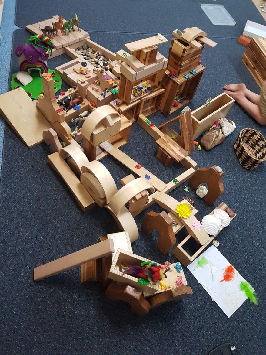 Wooden blocks and toys arranged in an intricate construction on a blue mat.
