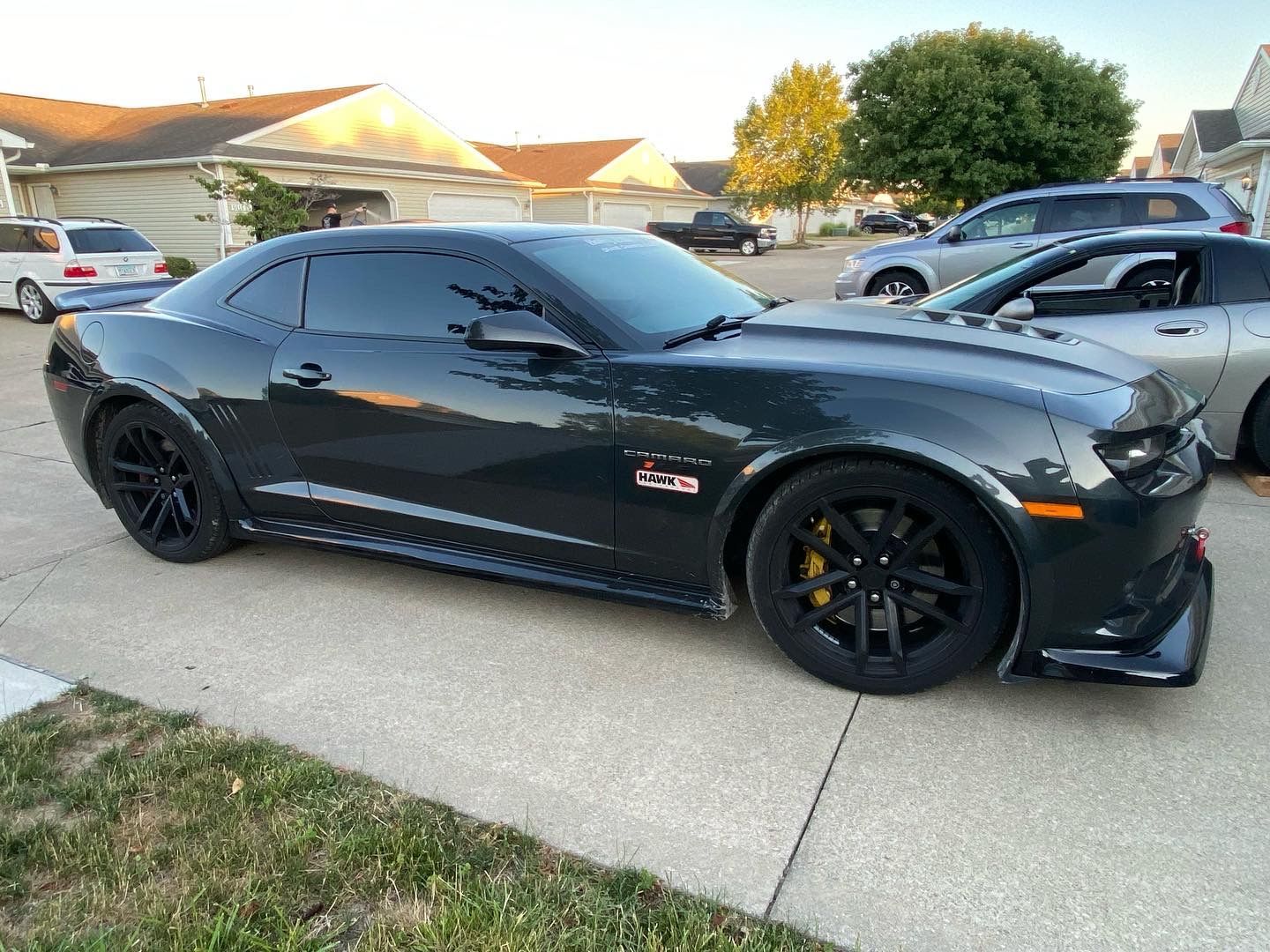 A black car is parked in a driveway next to a house.