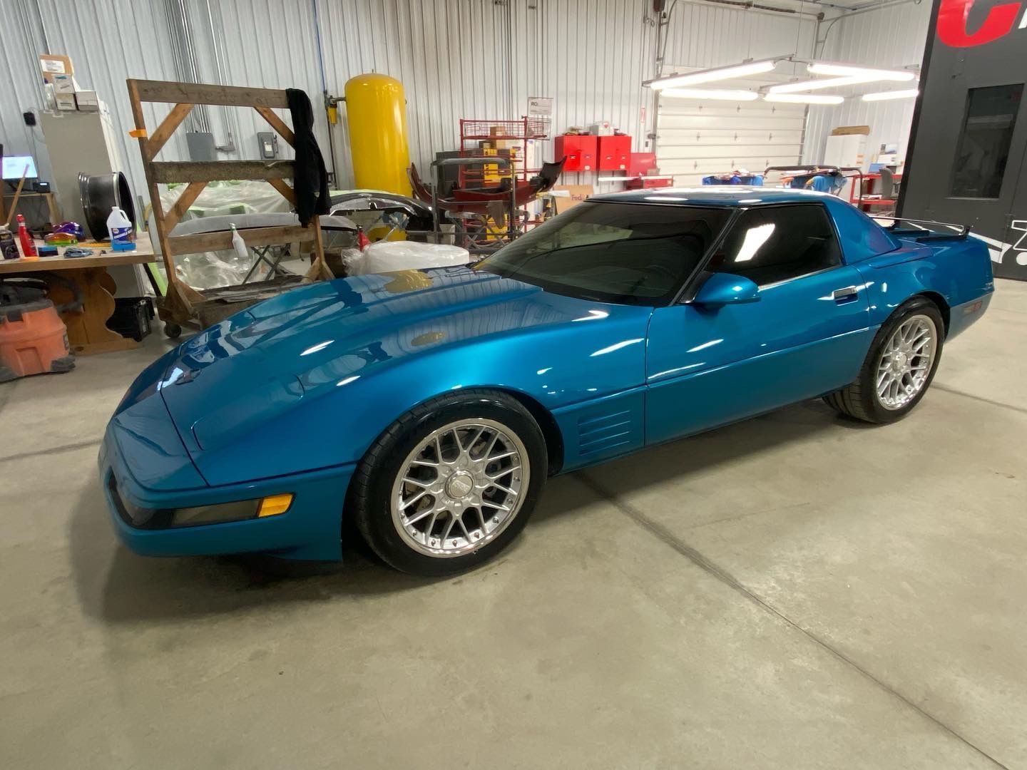 A blue corvette is parked in a garage.