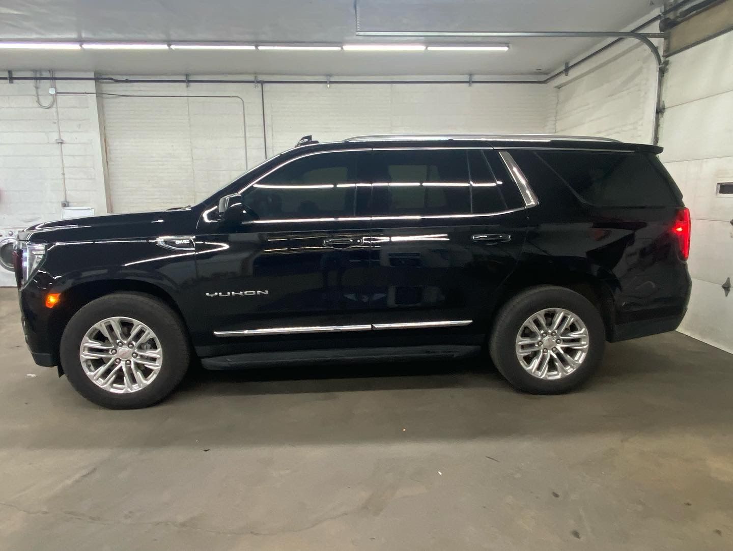 A black suv is parked in a garage next to a garage door.