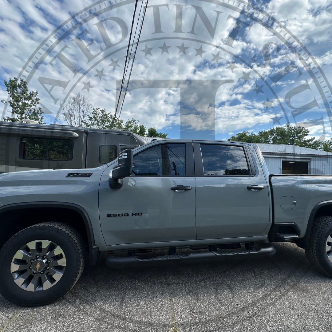 A gray truck is parked in a gravel lot.