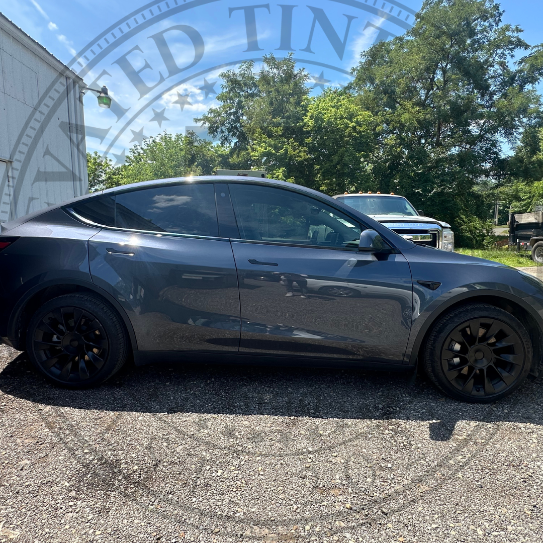 A tesla model y is parked in a gravel lot.