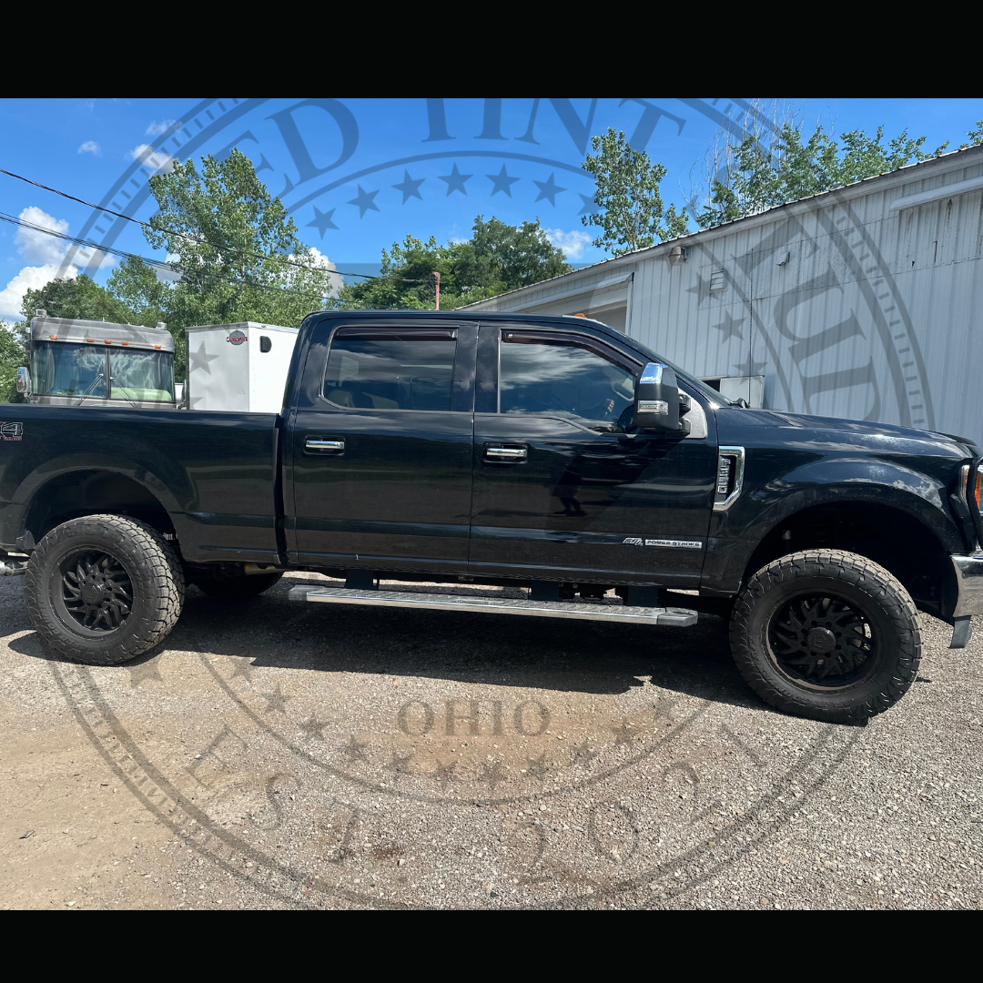 A black pickup truck is parked in a gravel lot in front of a building.