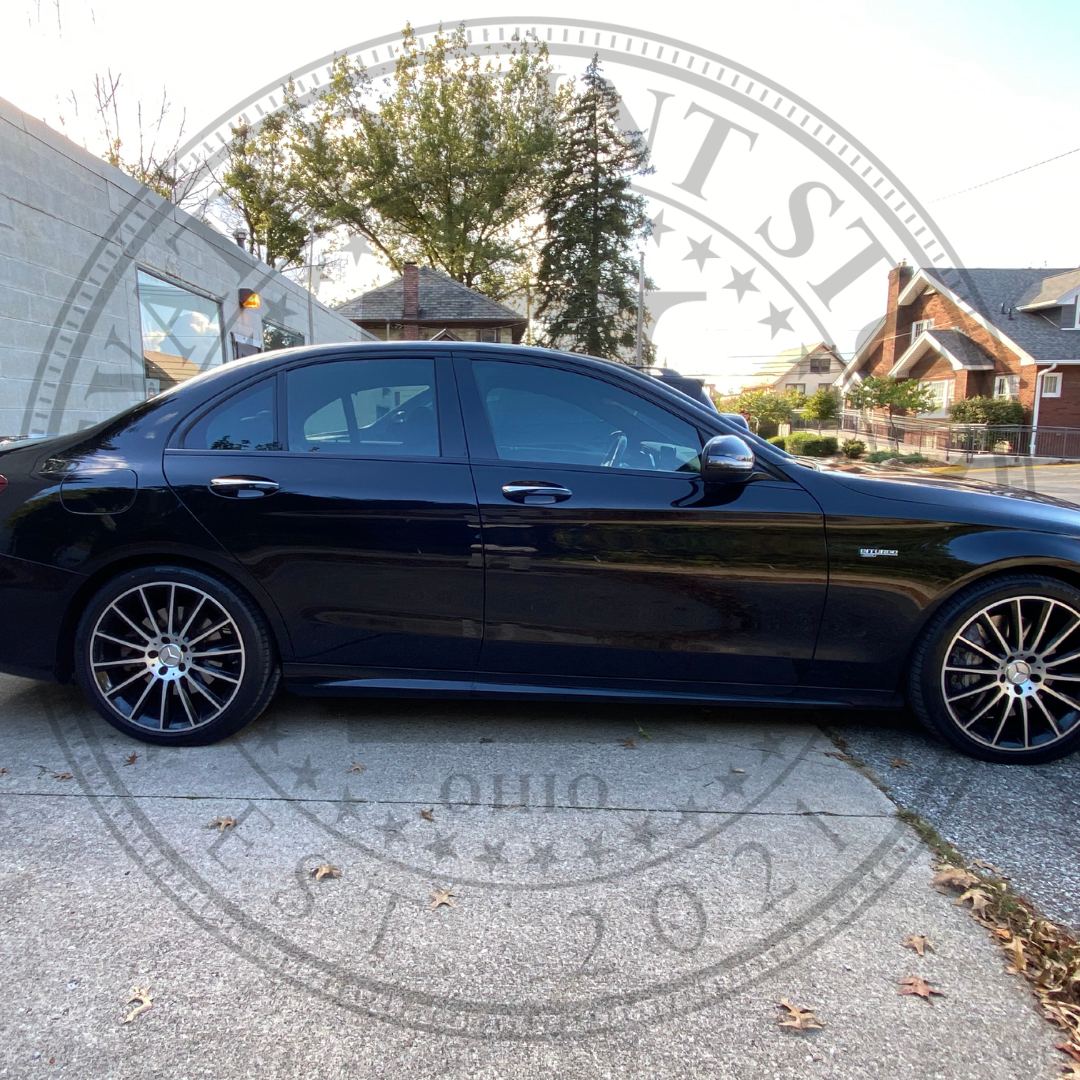 A black car is parked on the side of the road.
