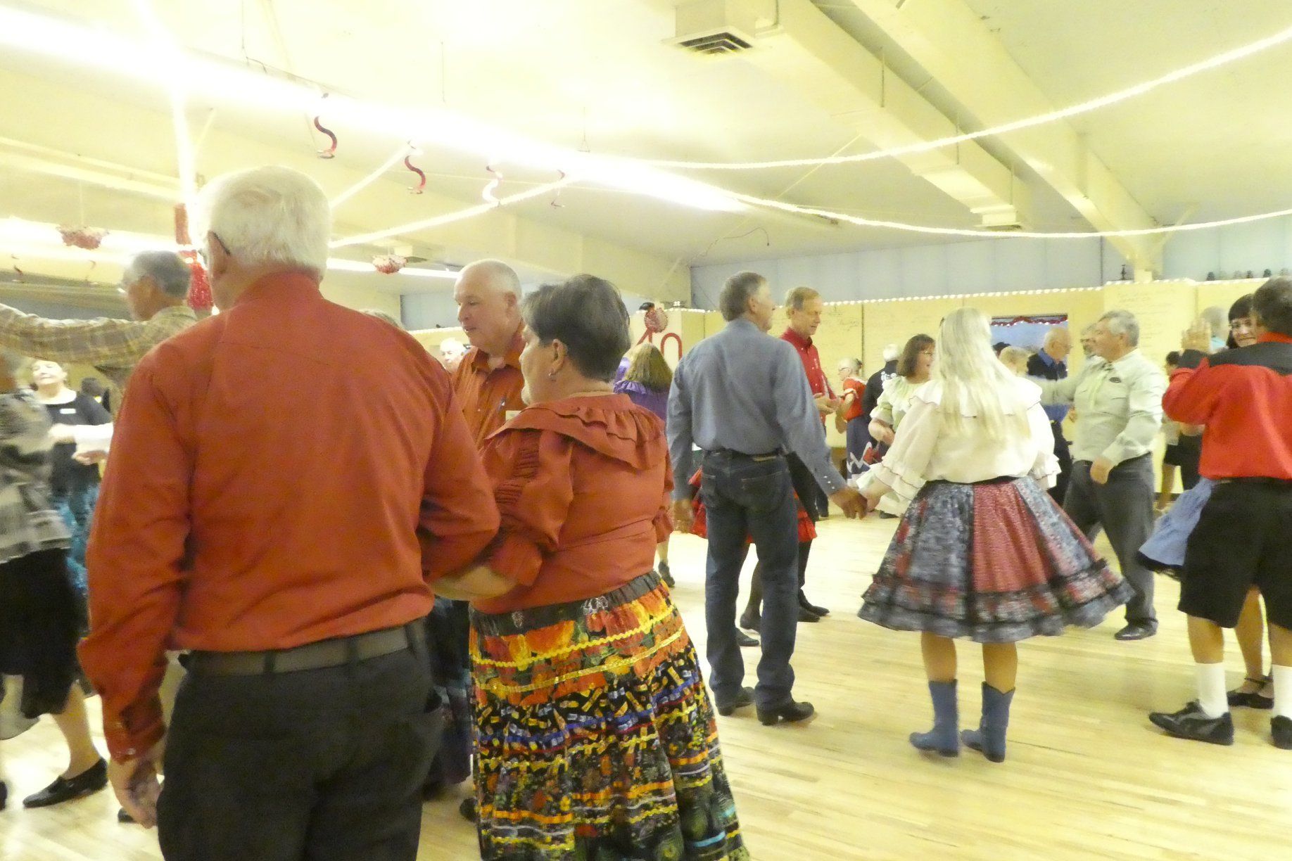 Group dancing in a bright room, with one person leading a raised hand and others smiling nearby