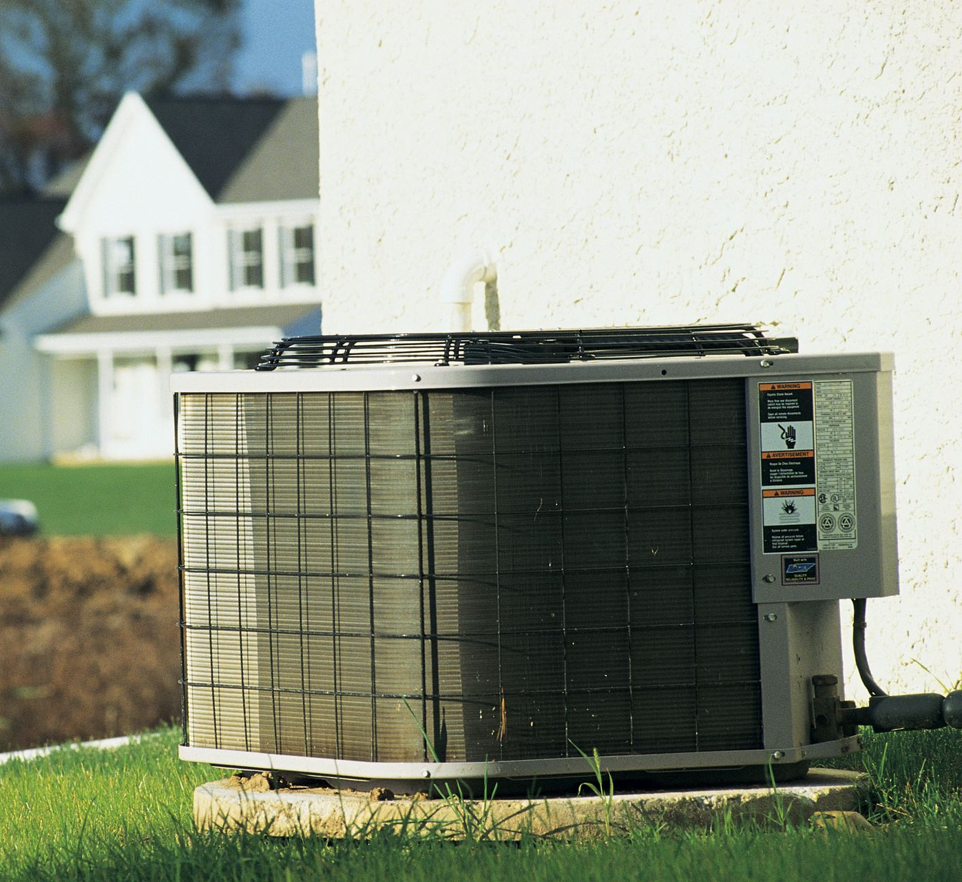 Under-sink plumbing with garbage disposal and drainage pipes. Beige, white, and black components against a brown cabinet interior.