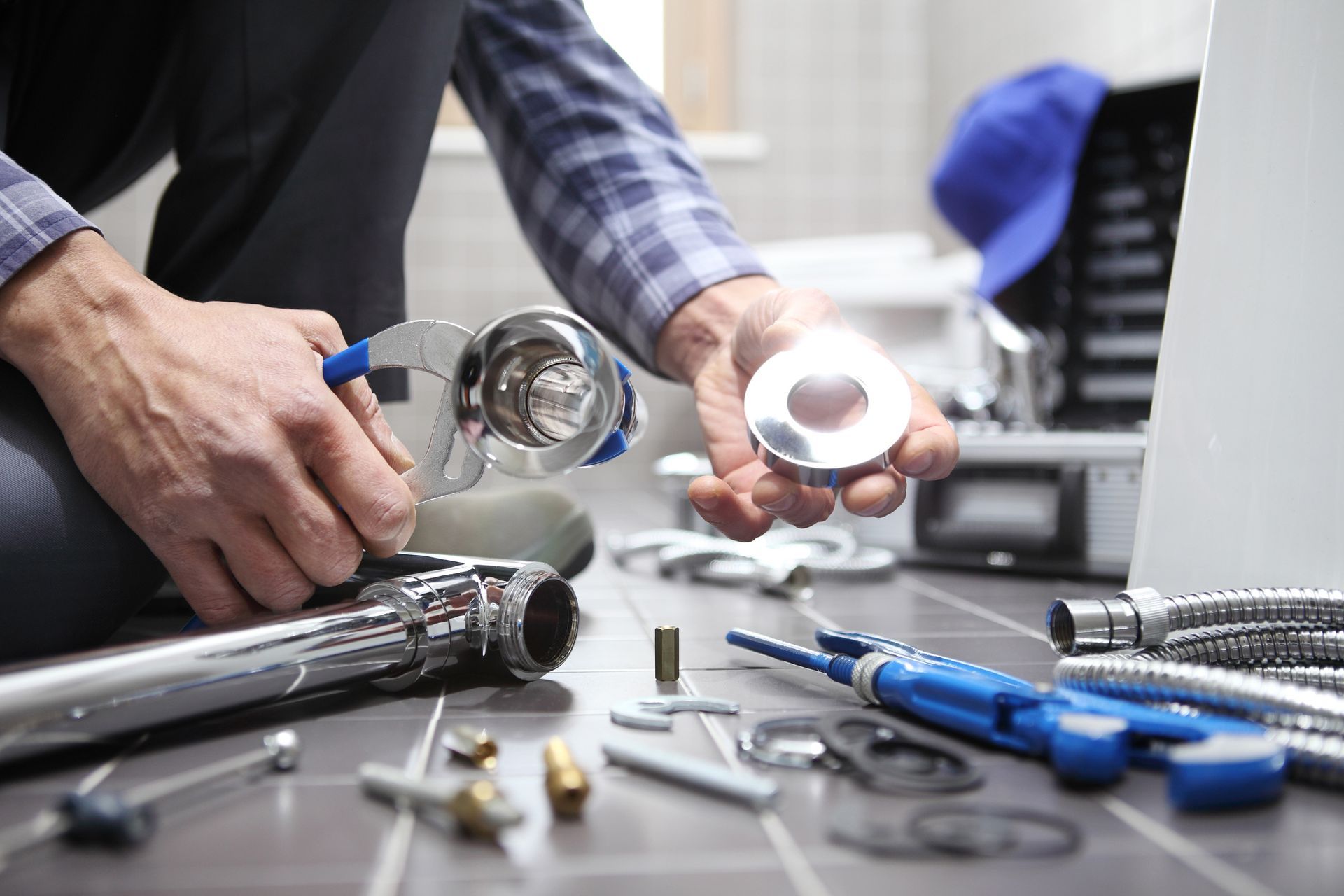 Plumber on floor, assembling sink drain parts with wrench and chrome plumbing, bathroom.