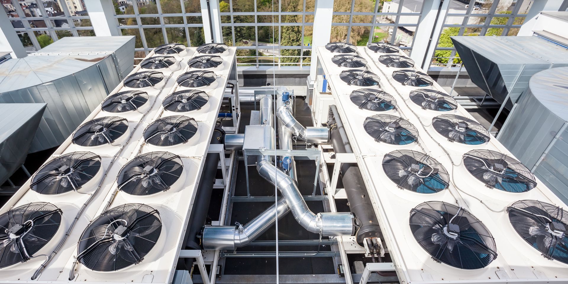 Rooftop HVAC units with multiple fans, metal pipes, and a metallic framework.