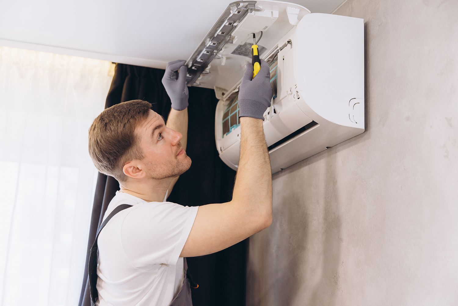 HVAC technician repairing wall-mounted air conditioner unit during professional service.