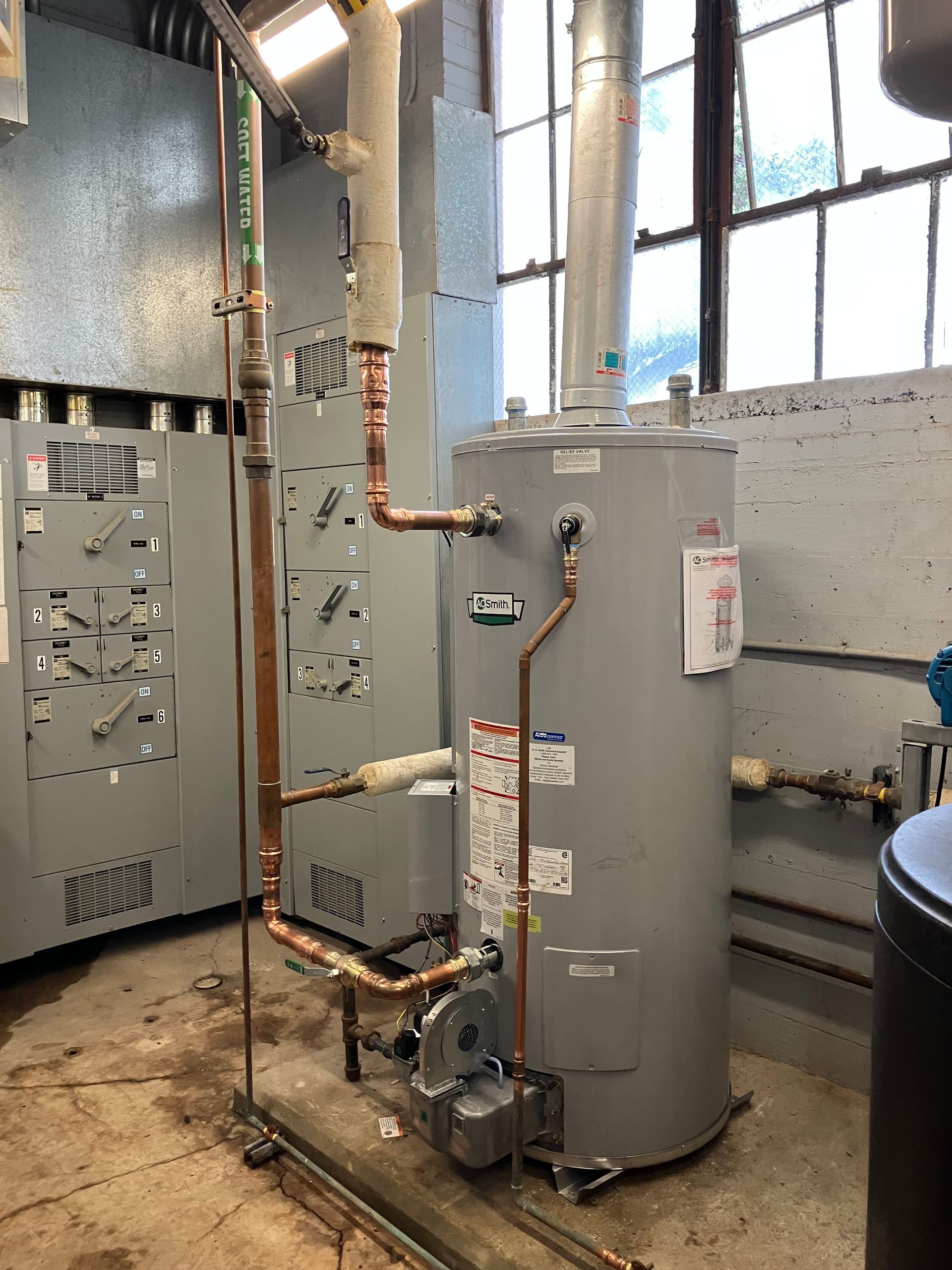 Complex heating system with pipes, pump, filter, and boiler installed on a wall in a corner of a room.