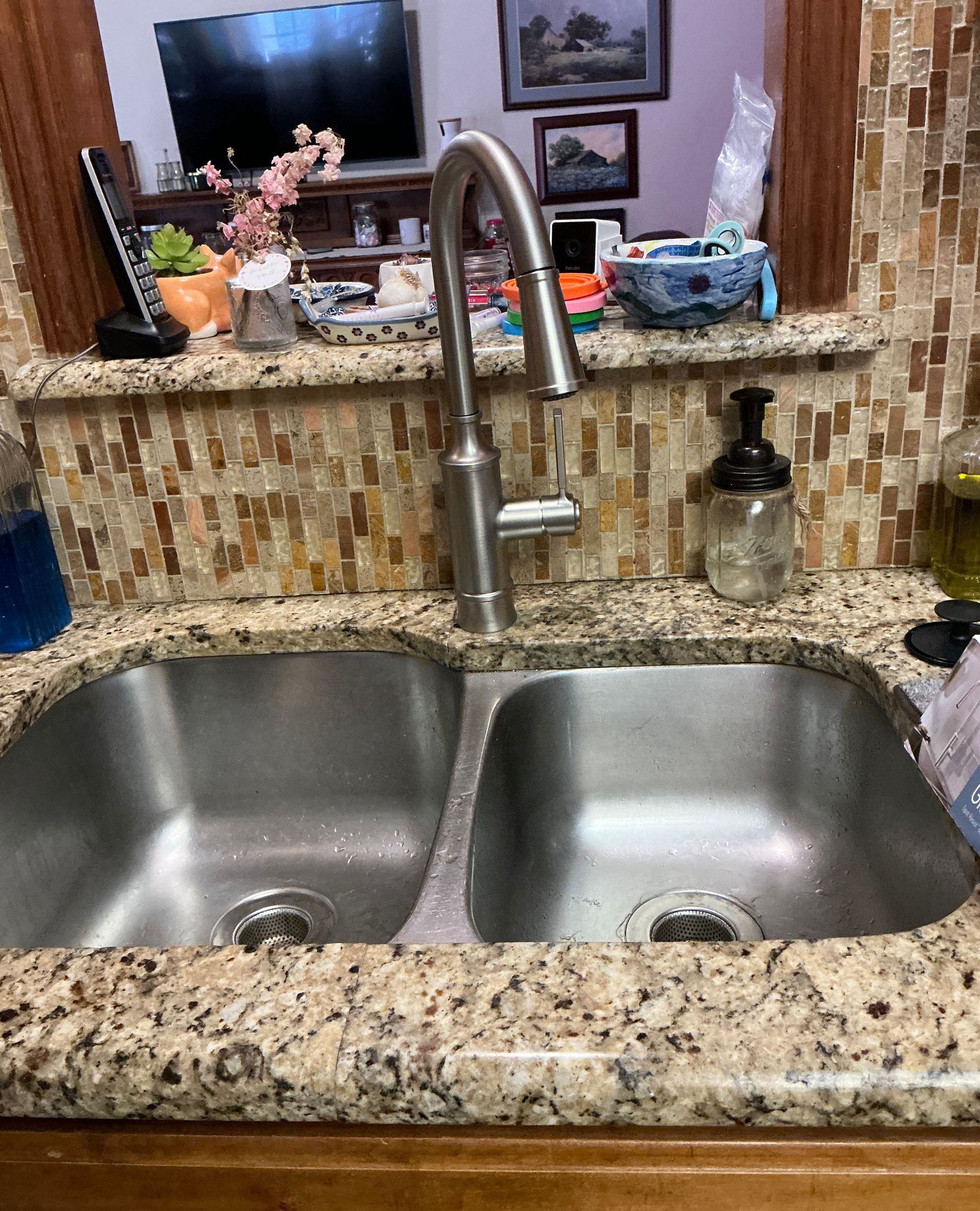 Plumber in blue denim, checking kitchen sink faucet. Holding clipboard, toolbox on counter.