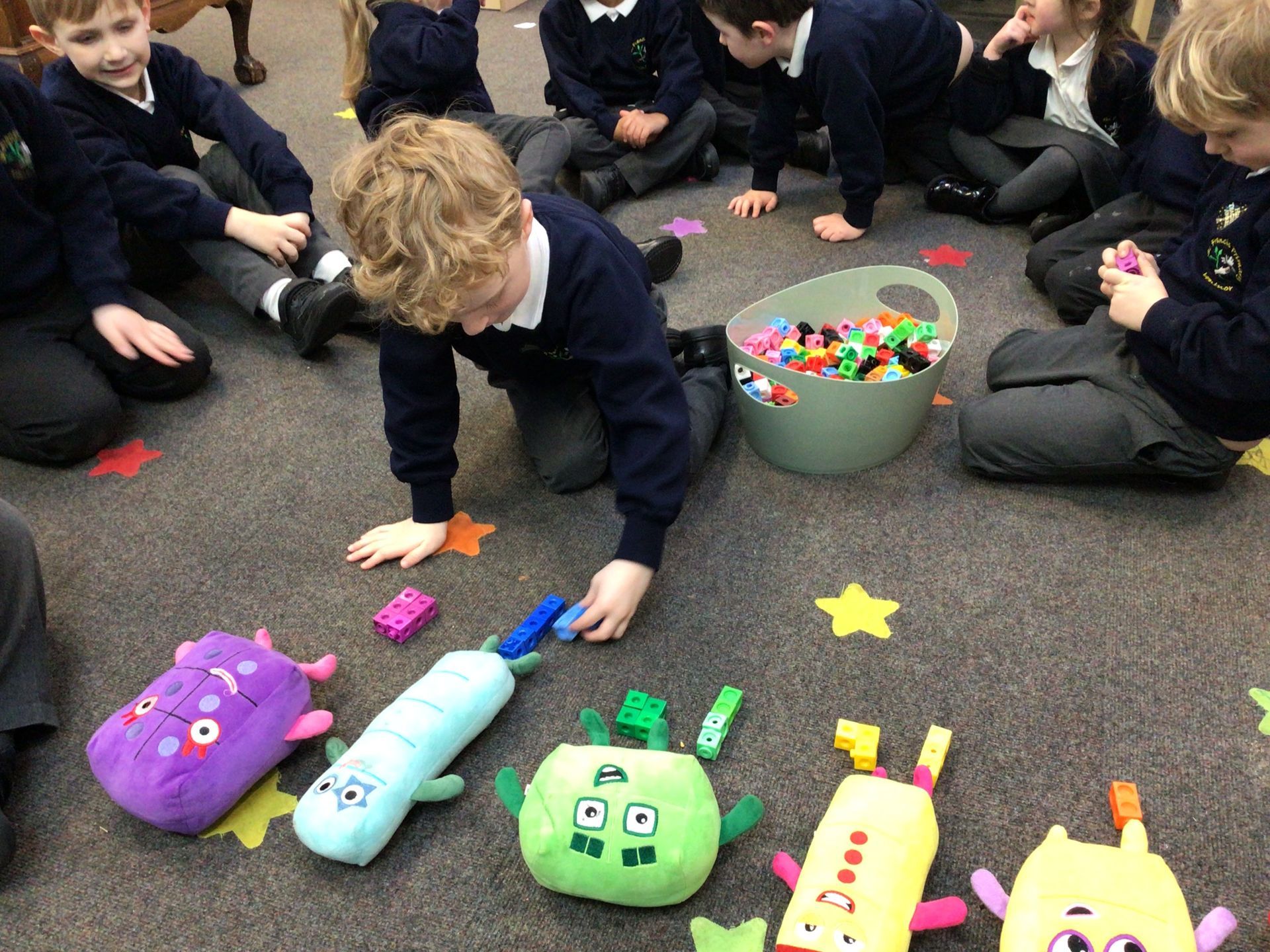 A group of children are sitting on the floor playing with stuffed animals.