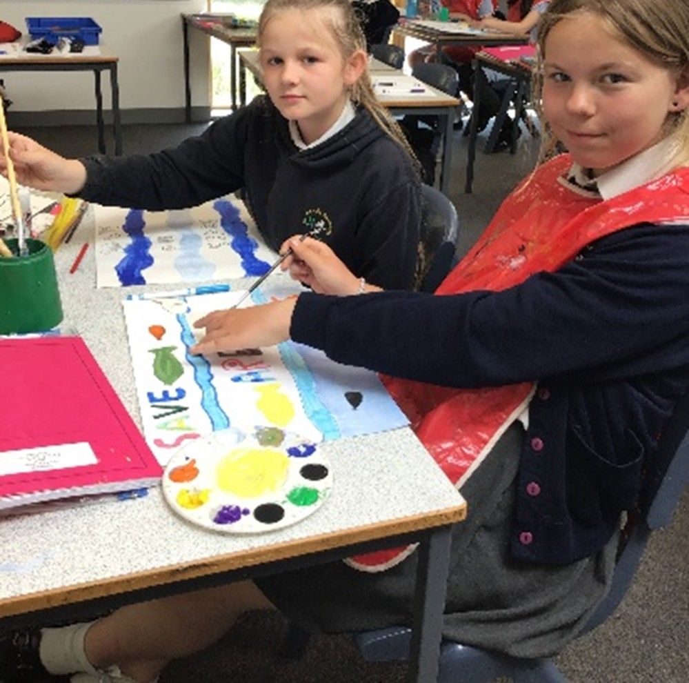 Two young girls are sitting at a table painting