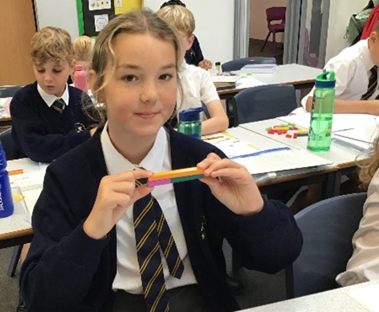 A girl in a school uniform is holding a rainbow colored pencil