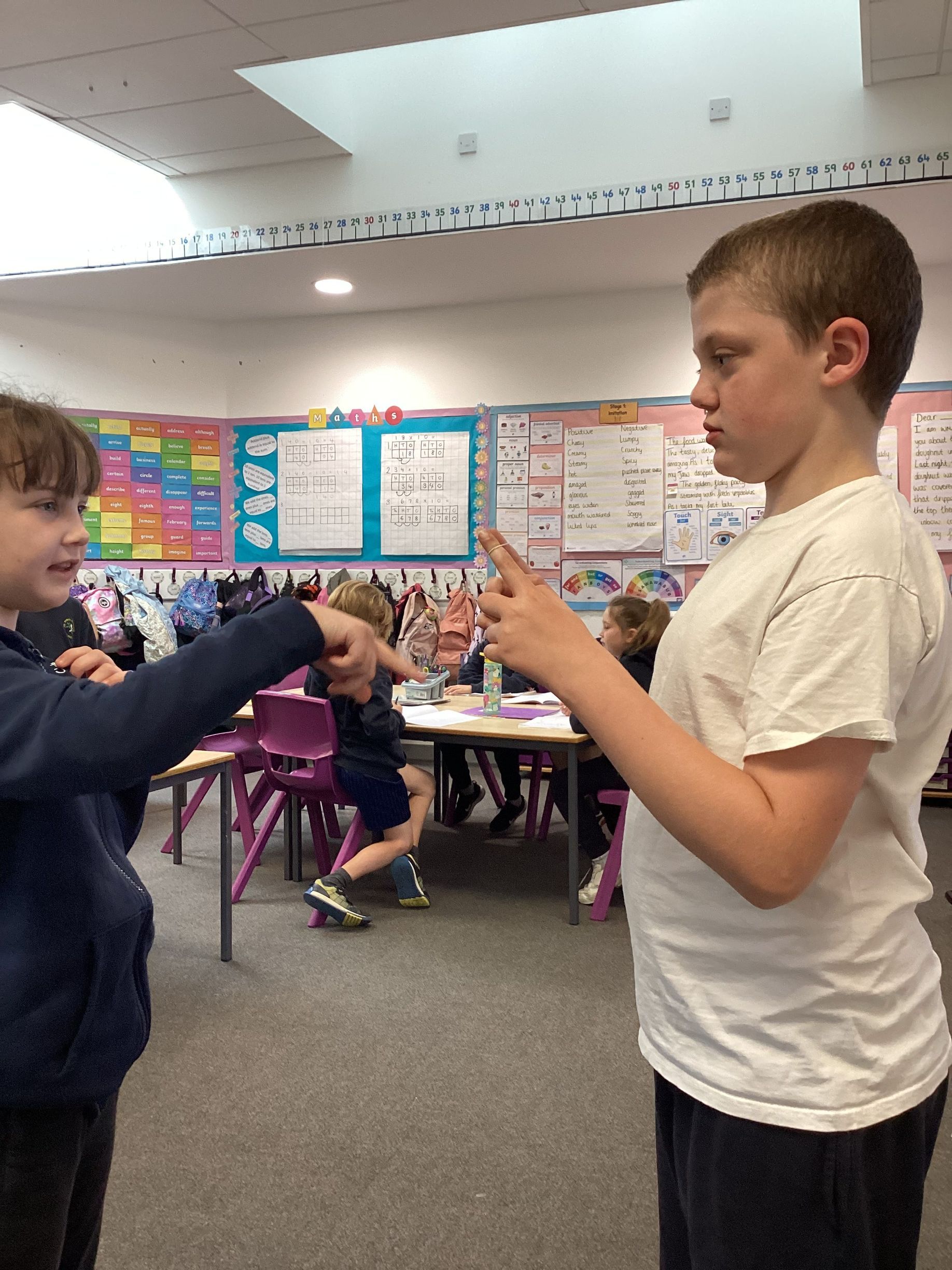 Two young boys are talking to each other in a classroom.