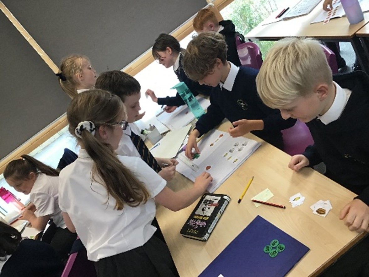 A group of children are sitting around a table in a classroom.