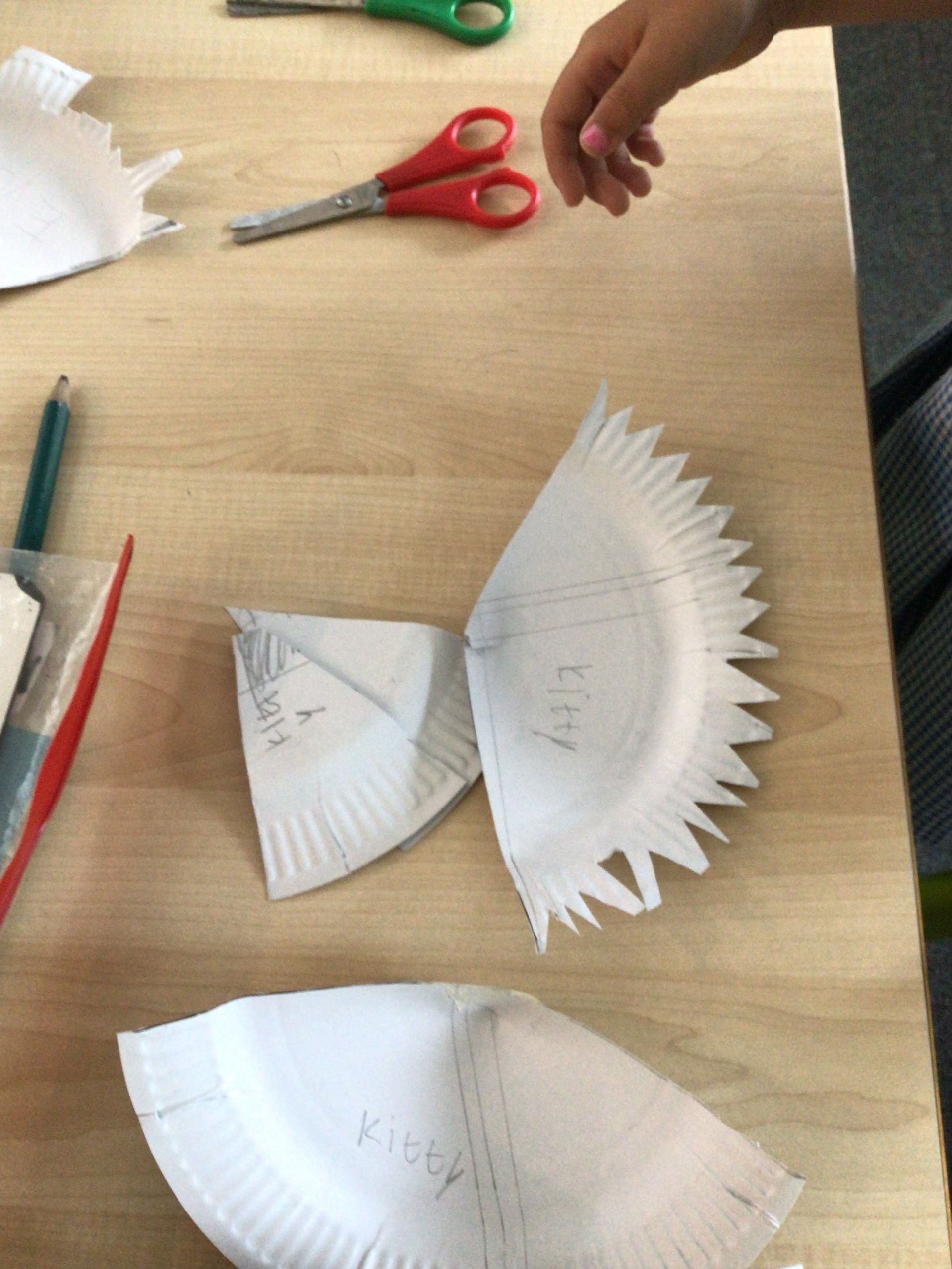 A person is cutting a paper plate with scissors on a table