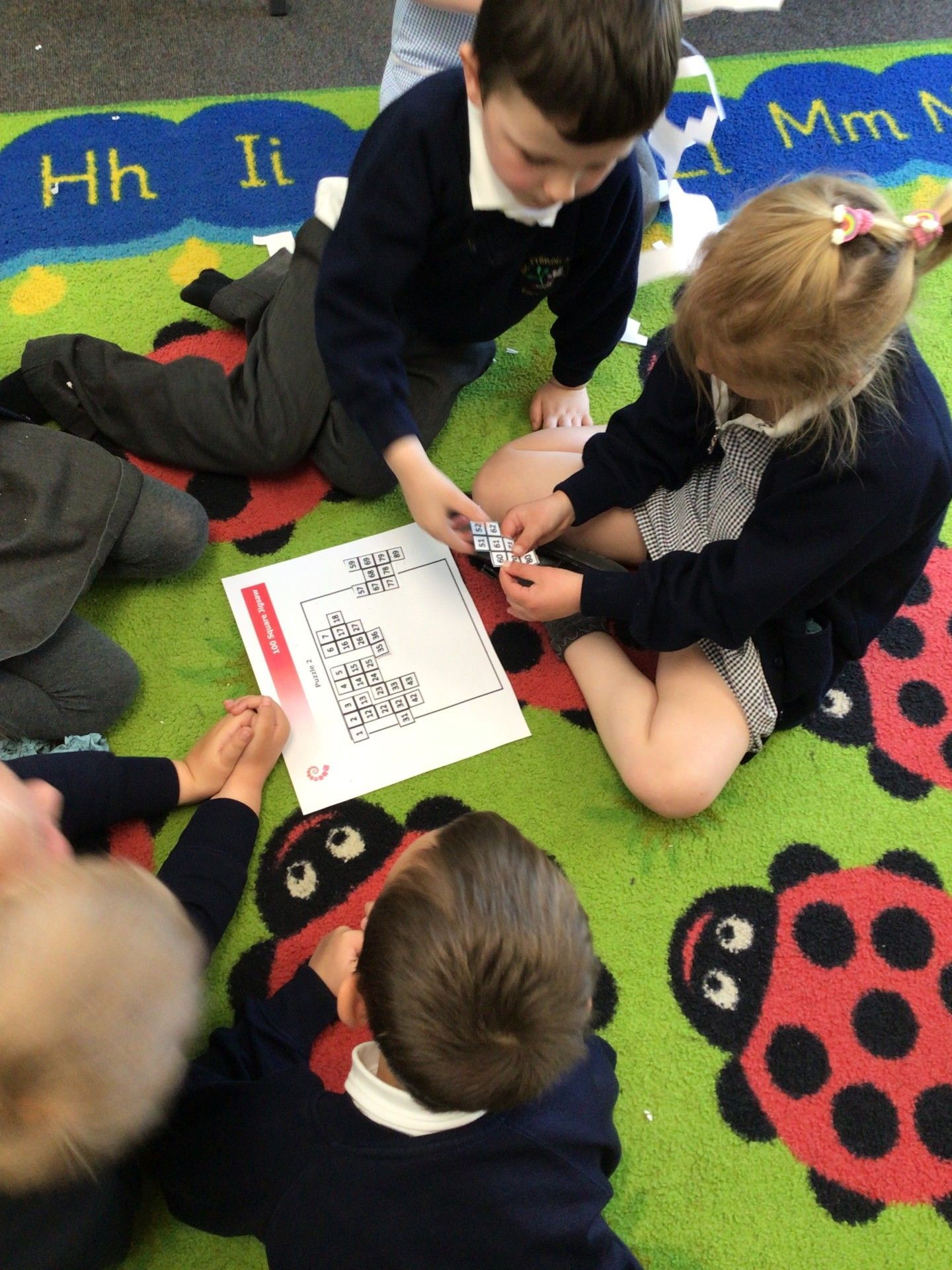 Children gathered on a colorful rug, looking at a book during a group activity.