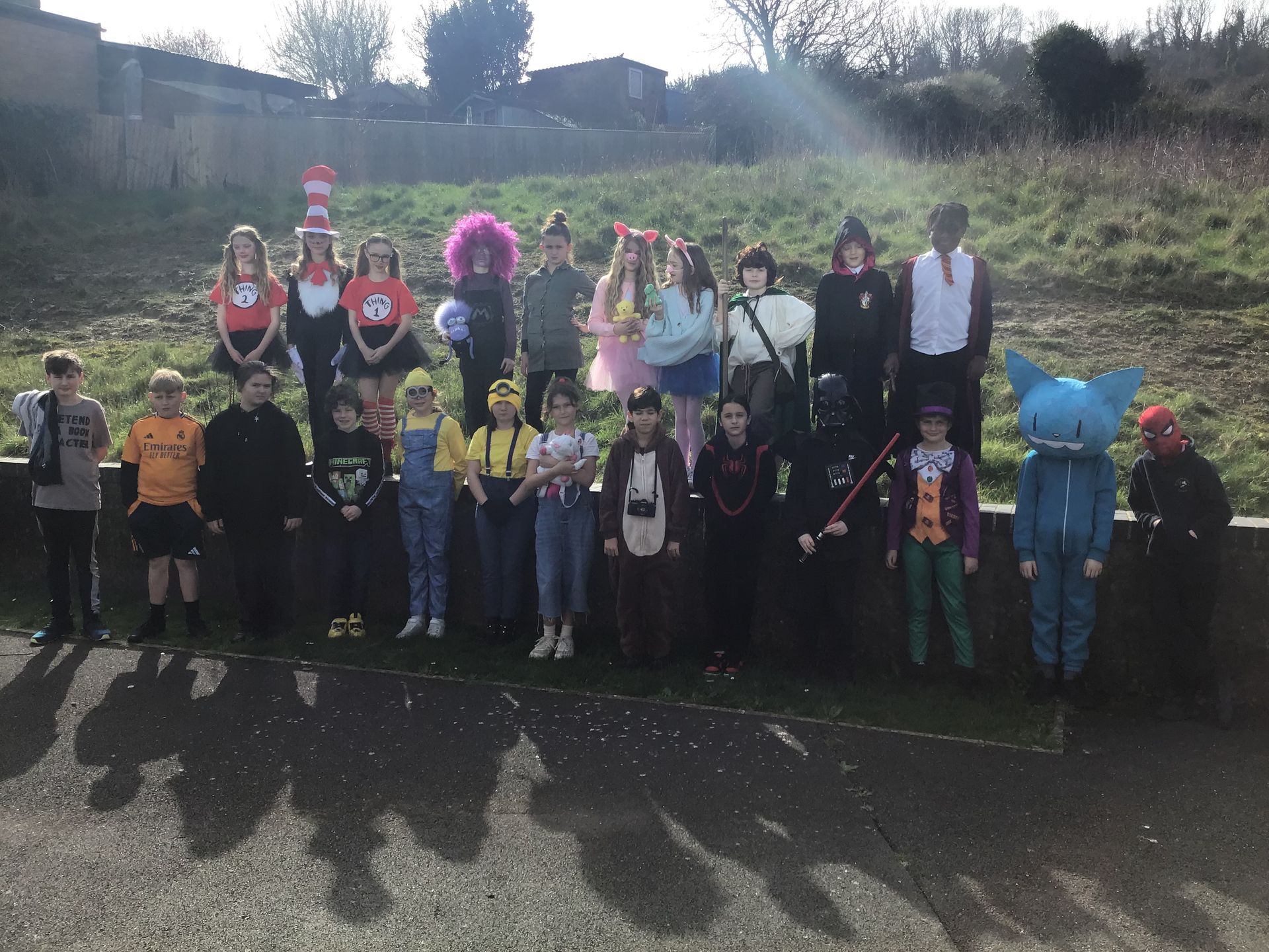 A group of children posing outdoors in a variety of colorful costumes for a school dress-up event.