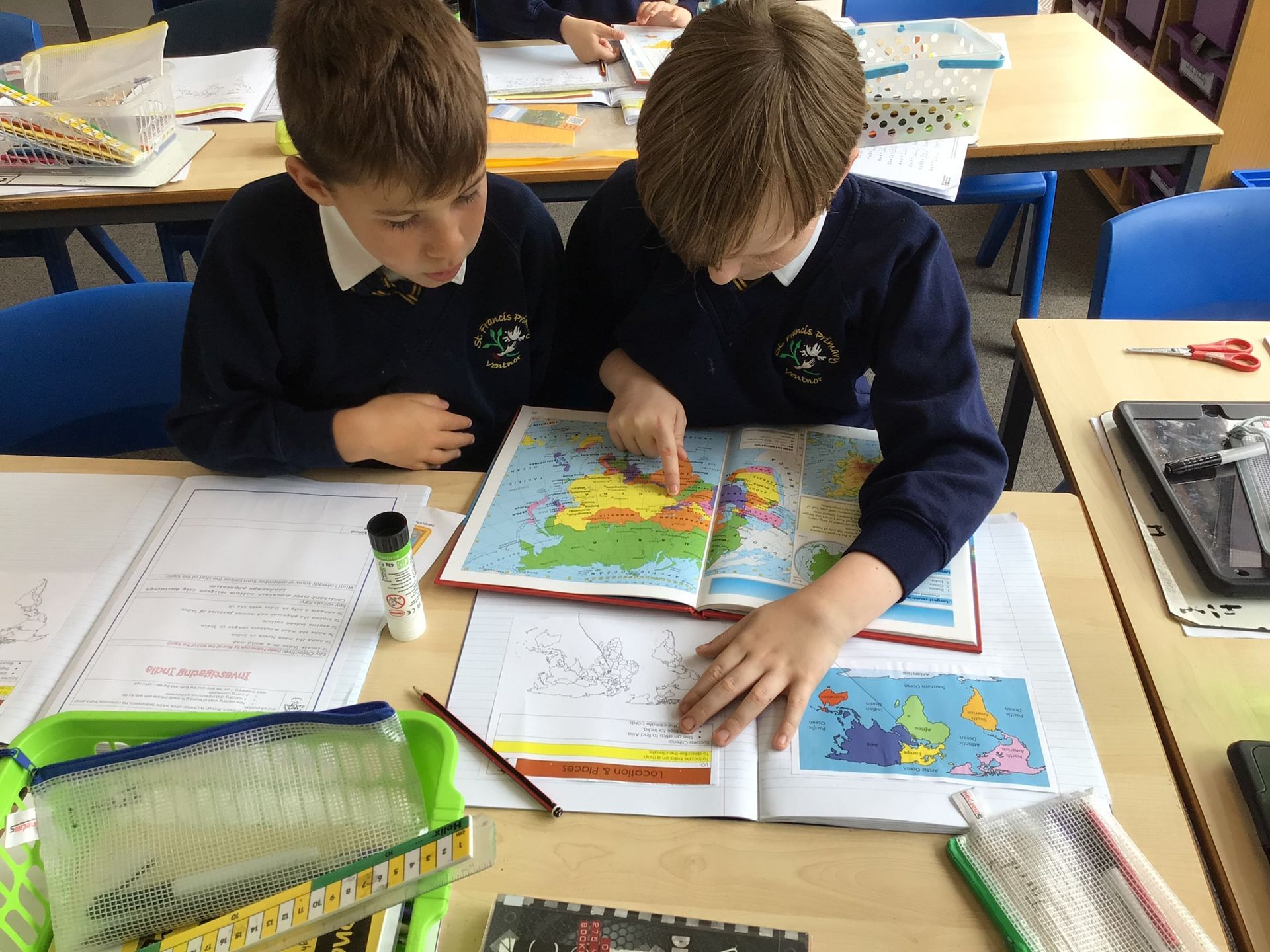 Two boys are sitting at a table looking at a map