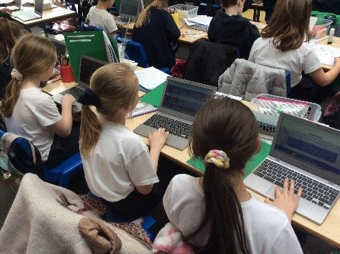 A group of children are using laptops in a classroom.