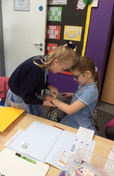 Two young girls are sitting at a table in a classroom